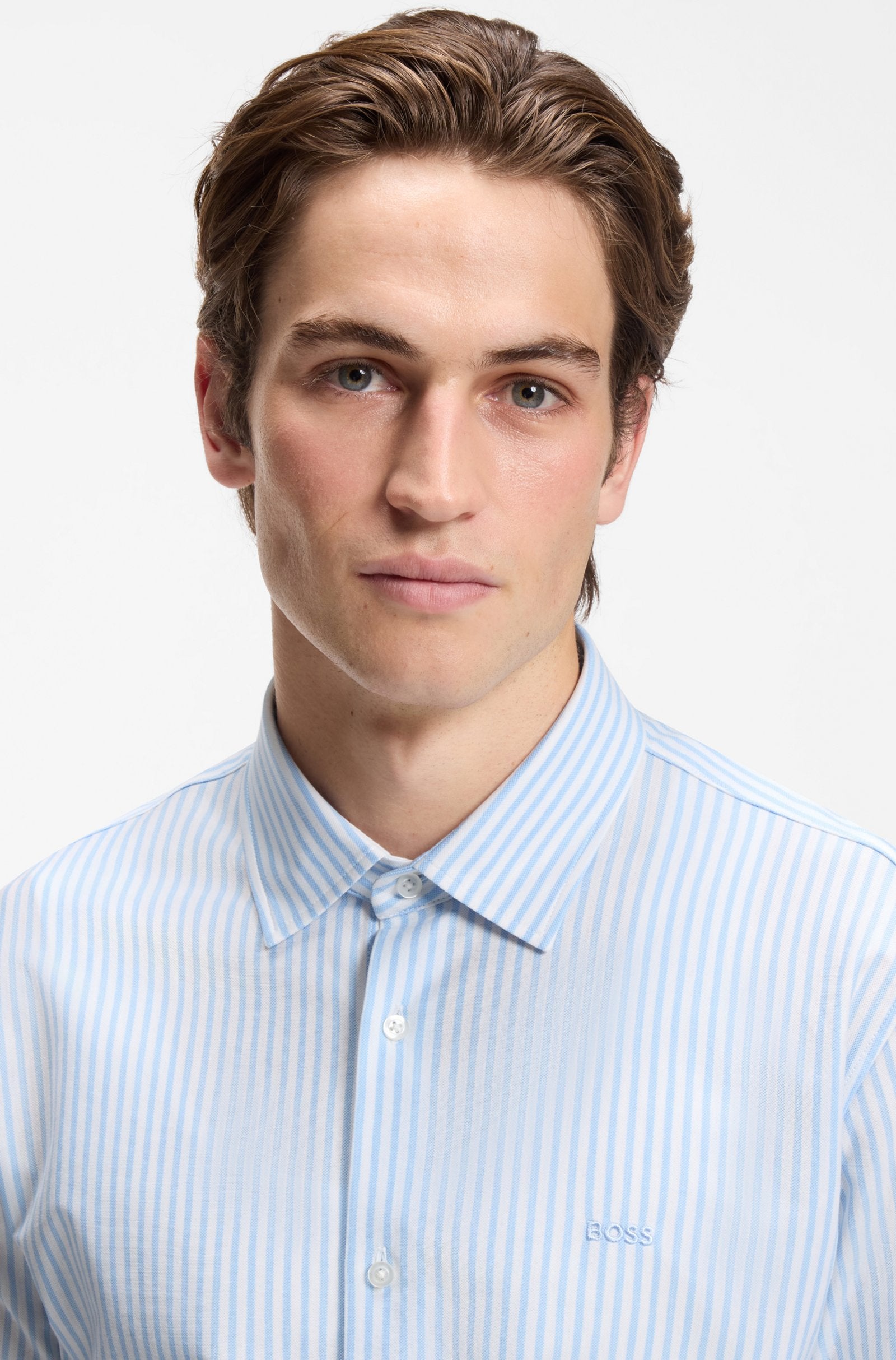 Detalhe do colarinho, botões e logótipo BOSS da camisa Slim Fit riscas azuis para homem em jersey de mistura de algodão.