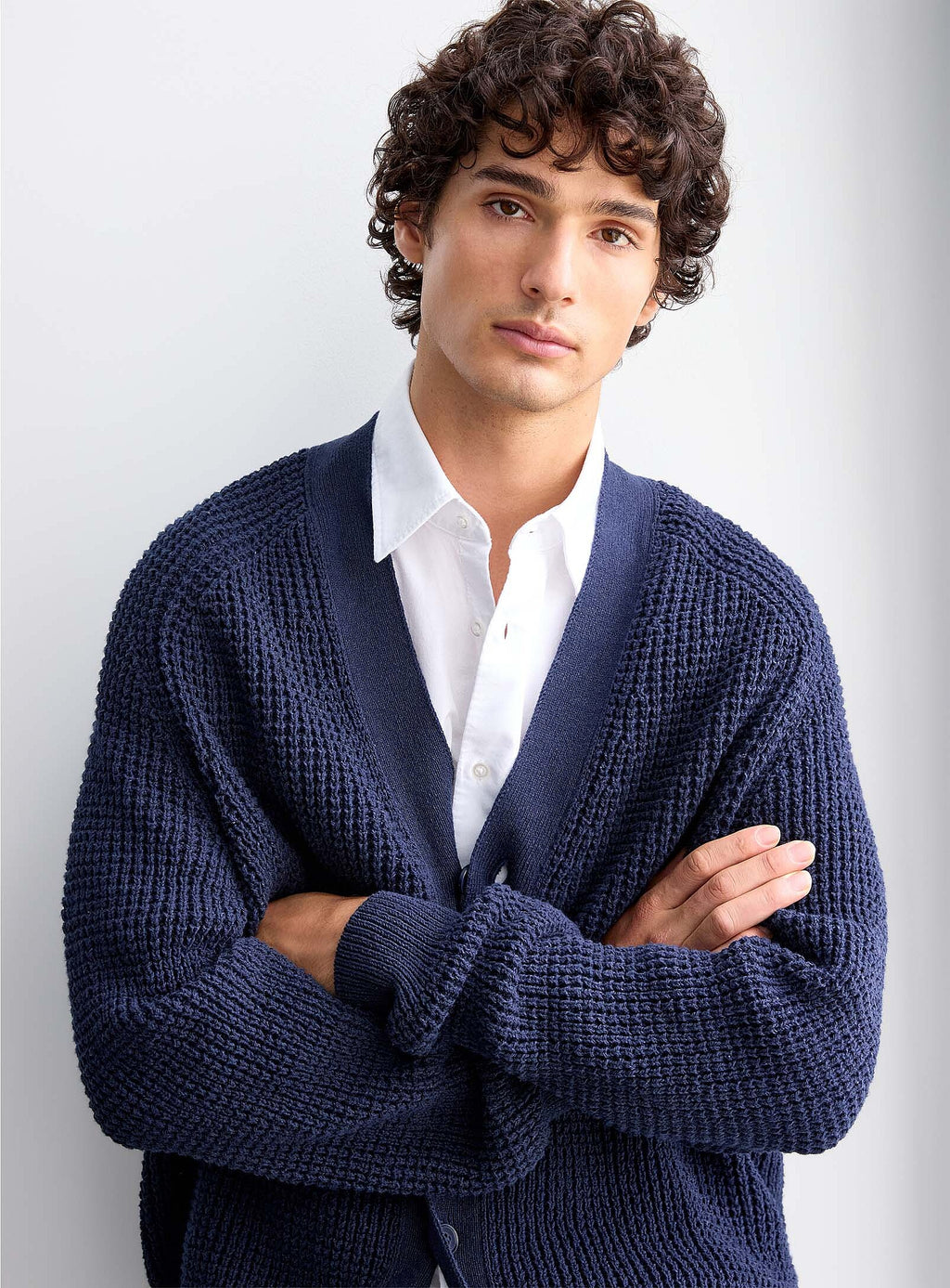 Pormenor frontal do cardigan de malha azul-marinho para homem da BOSS, evidenciando a textura em malha estruturada, o decote em V, a gola canelada, o fecho de botões e os acabamentos de elevada qualidade.