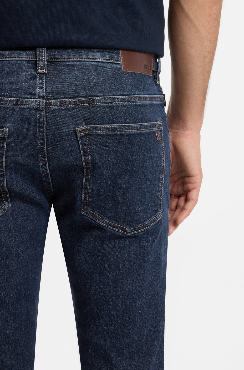 Detalhe dos bolsos traseiros das calças de ganga Delaware BOSS para homem em denim azul-escuro, com etiqueta em pele e costuras de contraste.