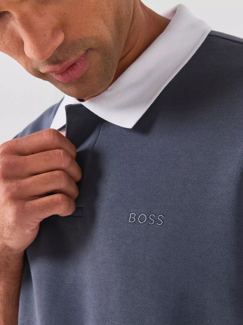 Pormenor do logótipo BOSS bordado no peito do polo para homem em jersey de algodão azul-escuro, destacando a assinatura discreta da marca e os acabamentos premium.