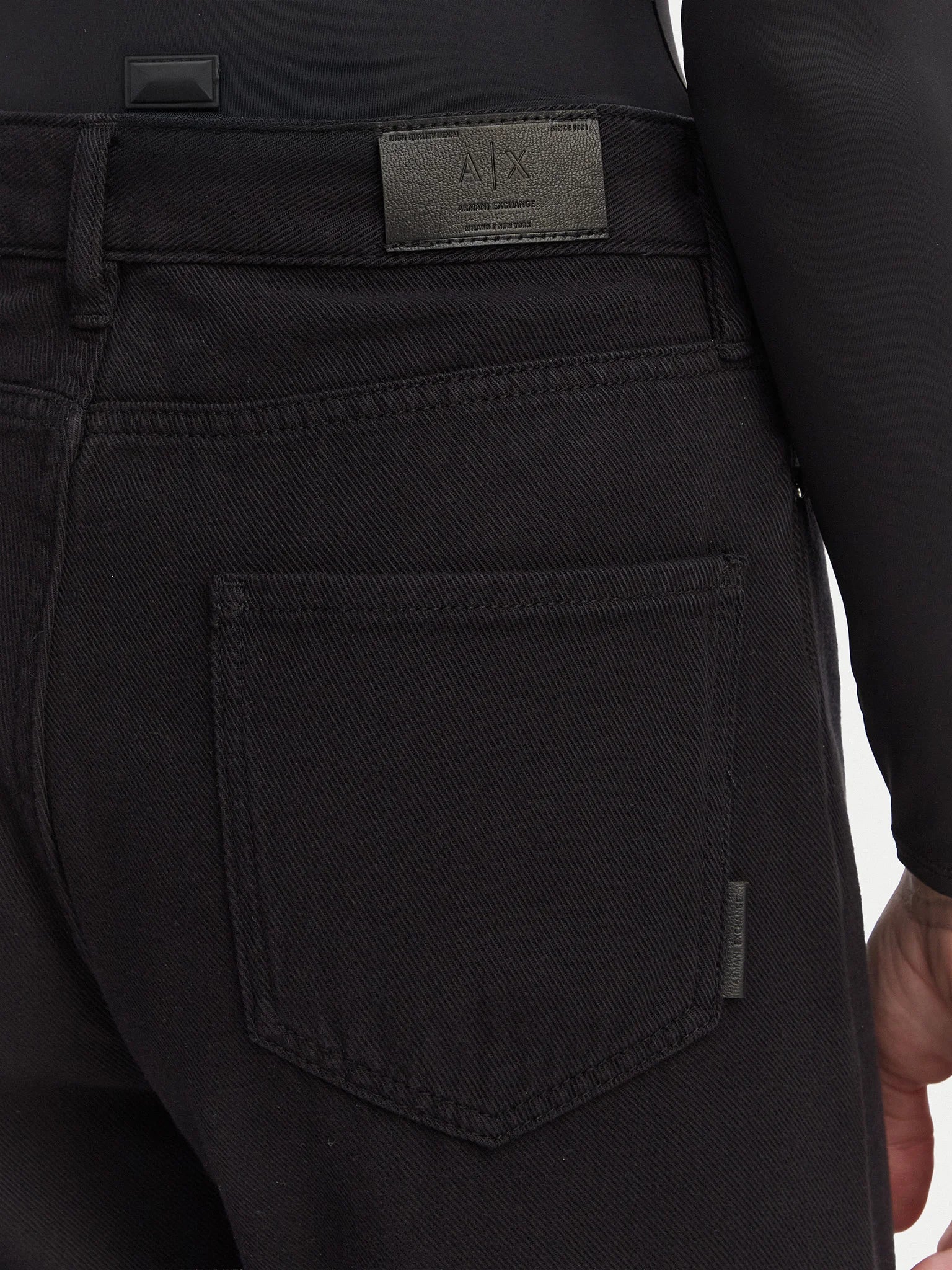 Detalhe do bolso e da etiqueta de pele com logótipo Armani Exchange na parte traseira das jeans Boyfriend Cropped pretas. 